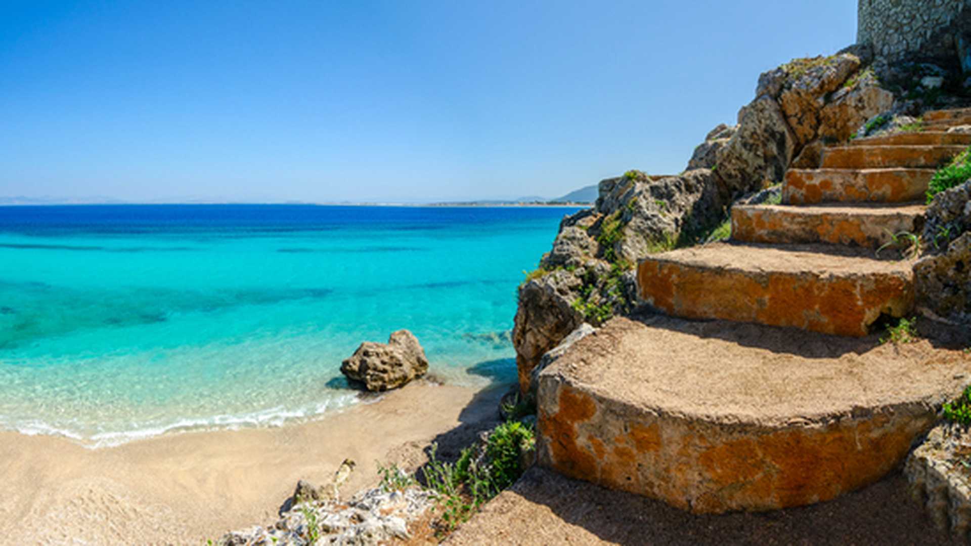 Stone stairs lead down to the beautiful beach of Agios Ioannis in Lefkas, Greece