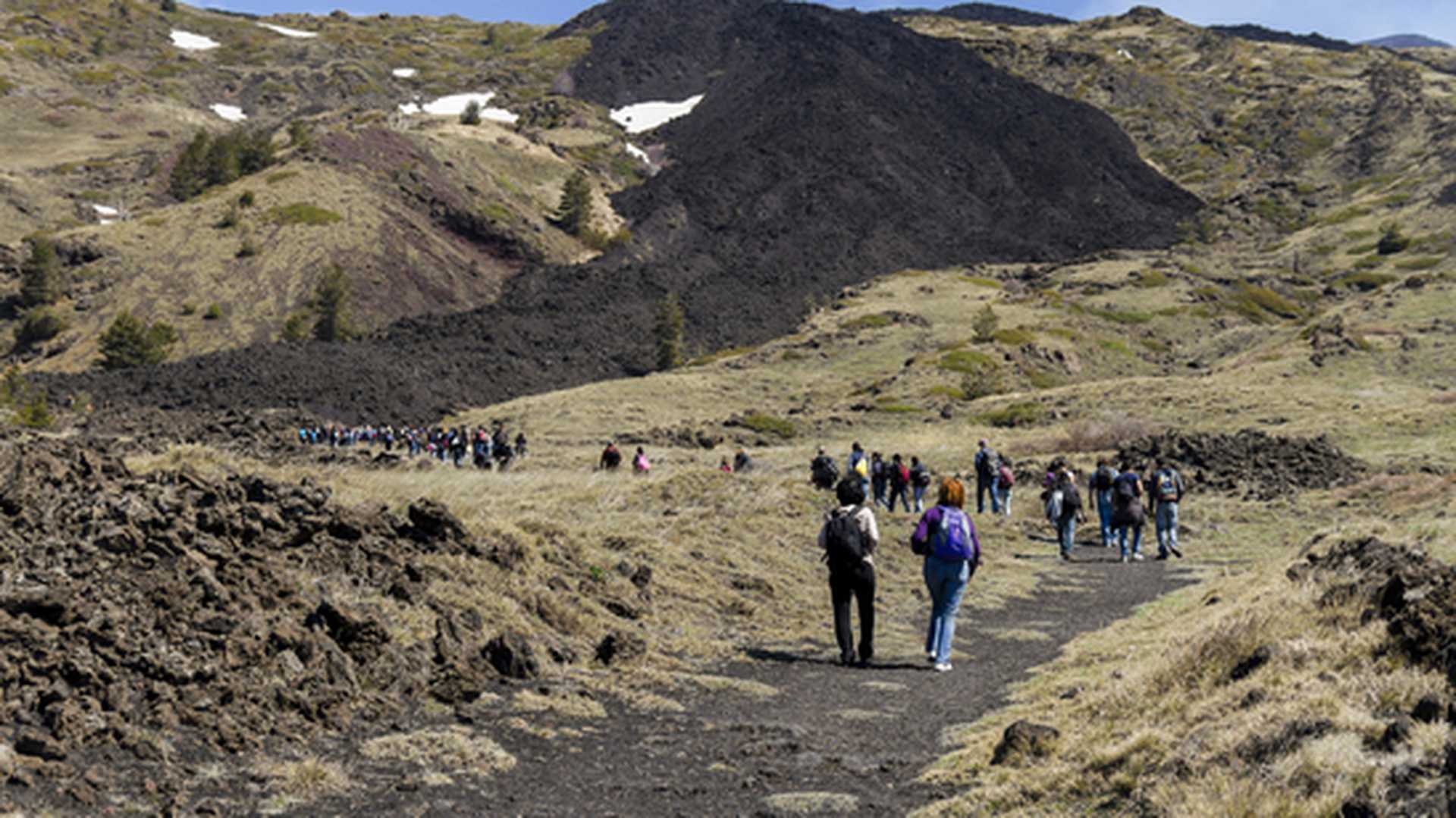 Visitors walk on cooled black lava on the slopes of Mount Etna, Sicily