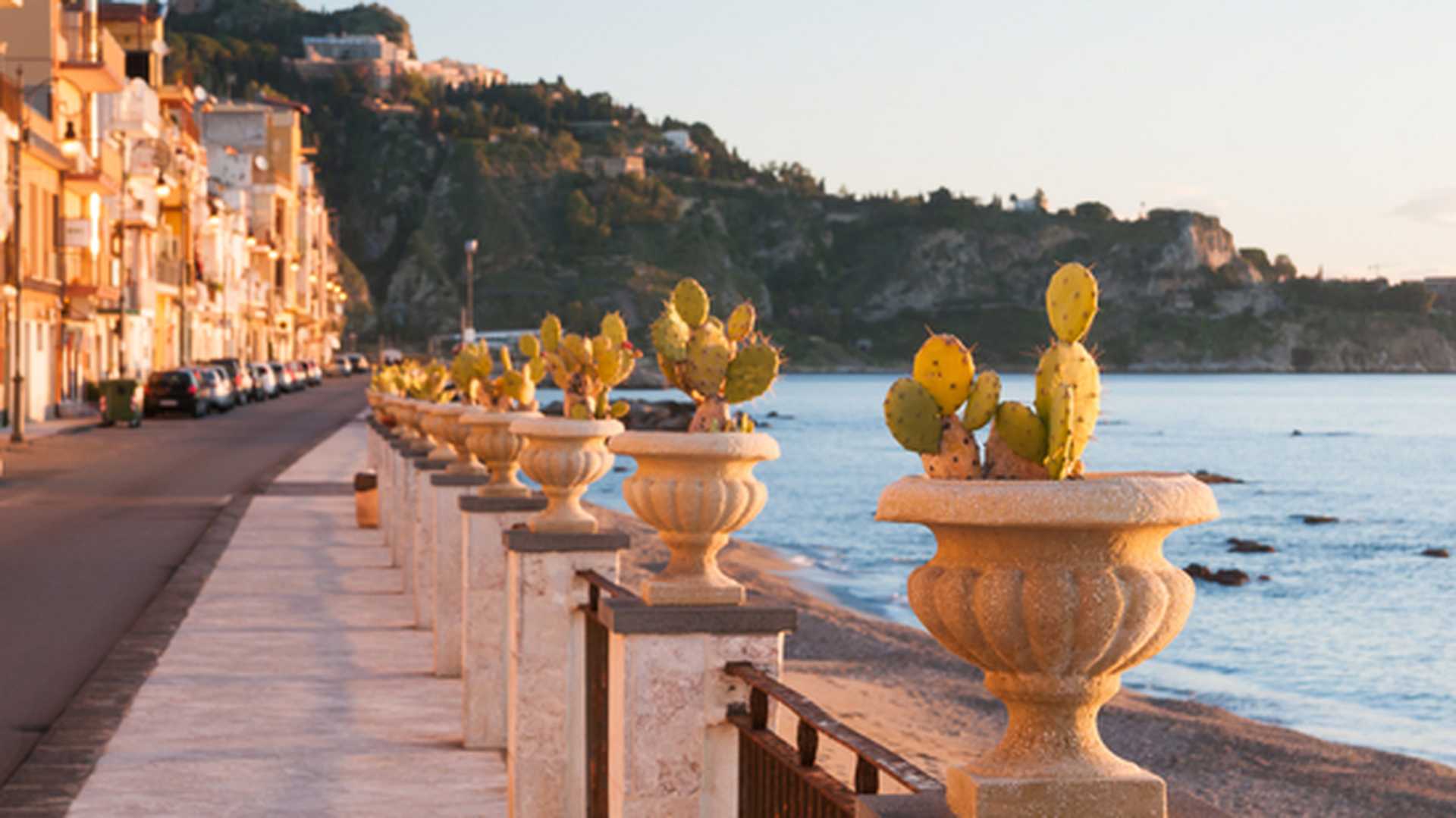 Potted cacti line a waterfront promenade in Giardini Naxos, Sicily