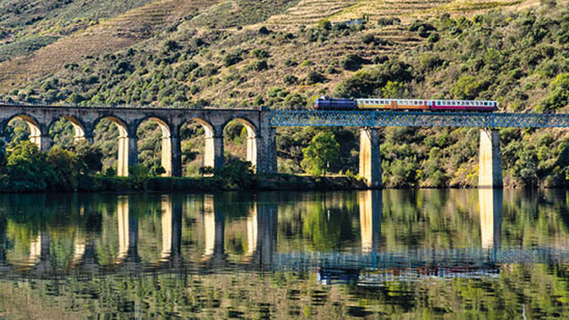 Train crossing a bridge through vinyards on the Douro Line, Portugal