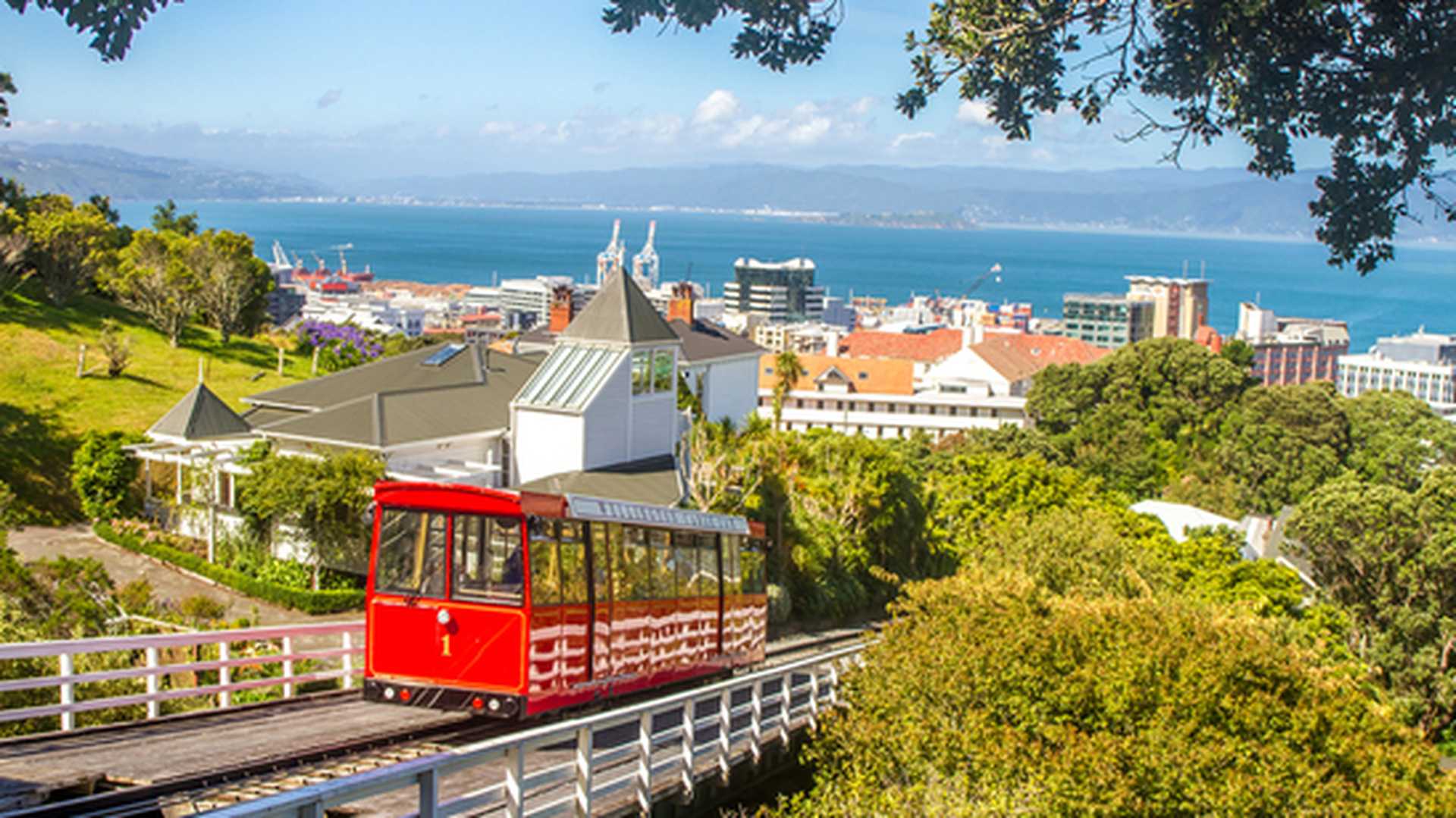 A red cable car travels up hill above the city of Wellington on New Zealand's North Island