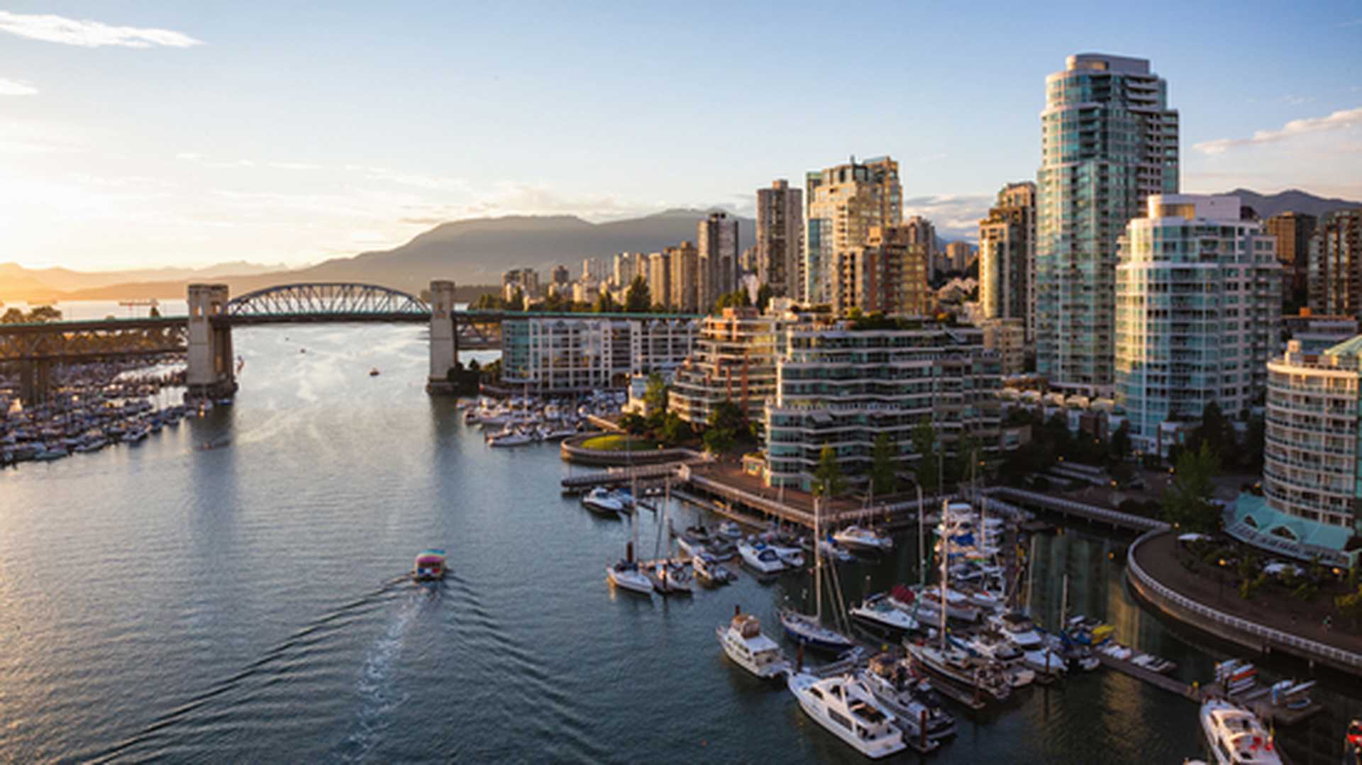 View of Downtown Vancouver and Burrard Bridge at False Creek during sunny sunset.