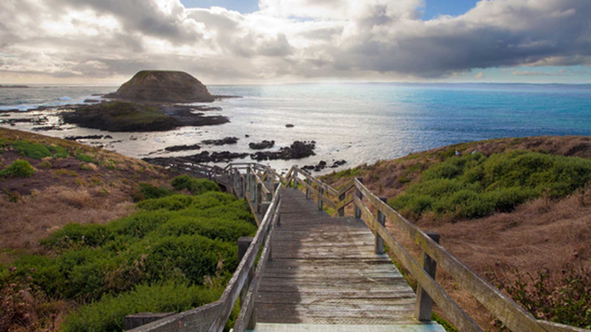 A view down a wooden staircase leading to the sea on Phillip Island, Australia