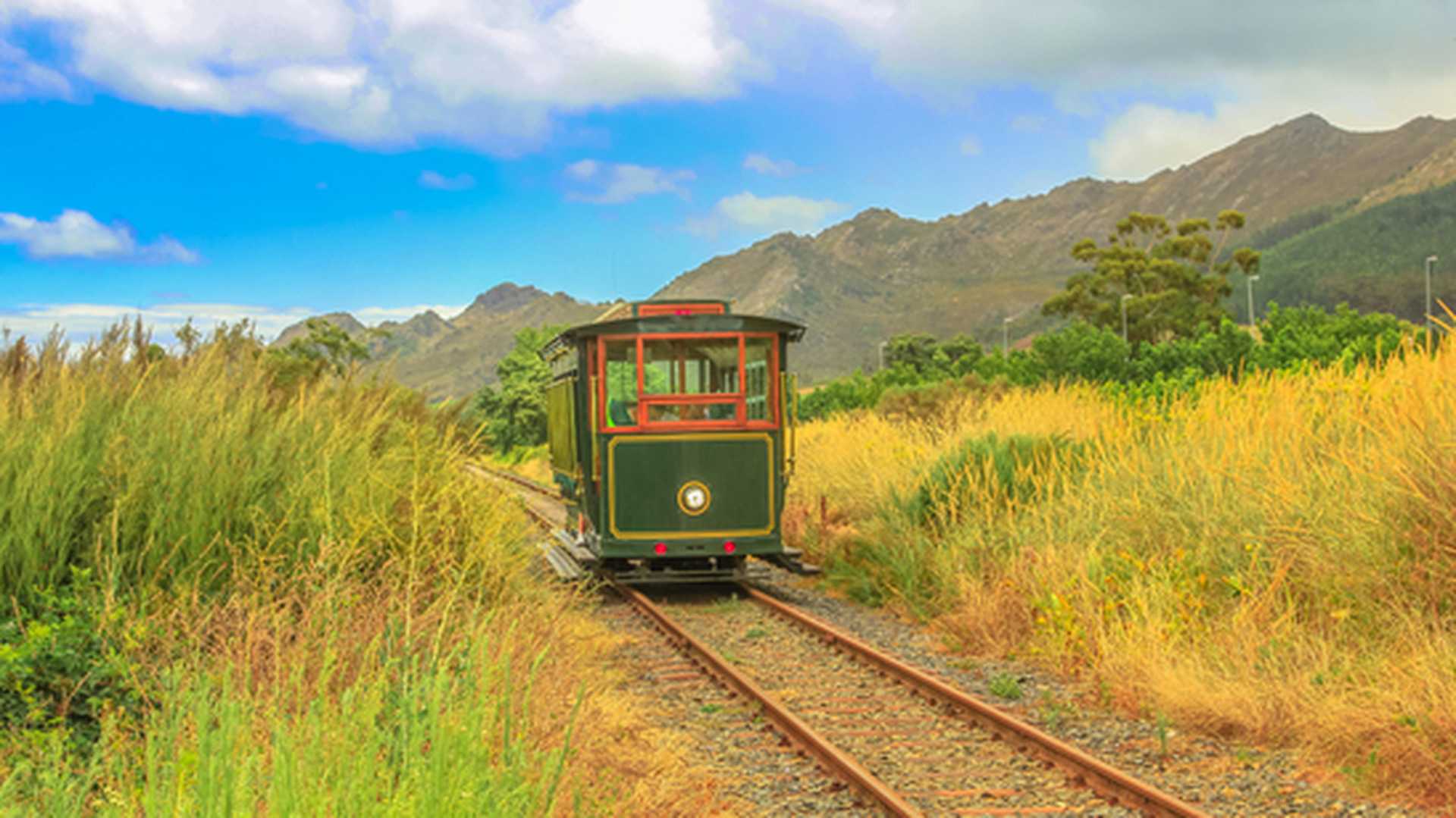 A vintage-style tram travels through the Franschhoek winelands in South Africa