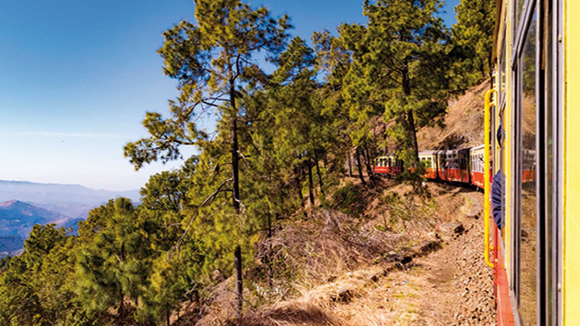 View from moving train on mountain slopes. Toy train from Shimla to Kalka in Himachal Pradesh, India