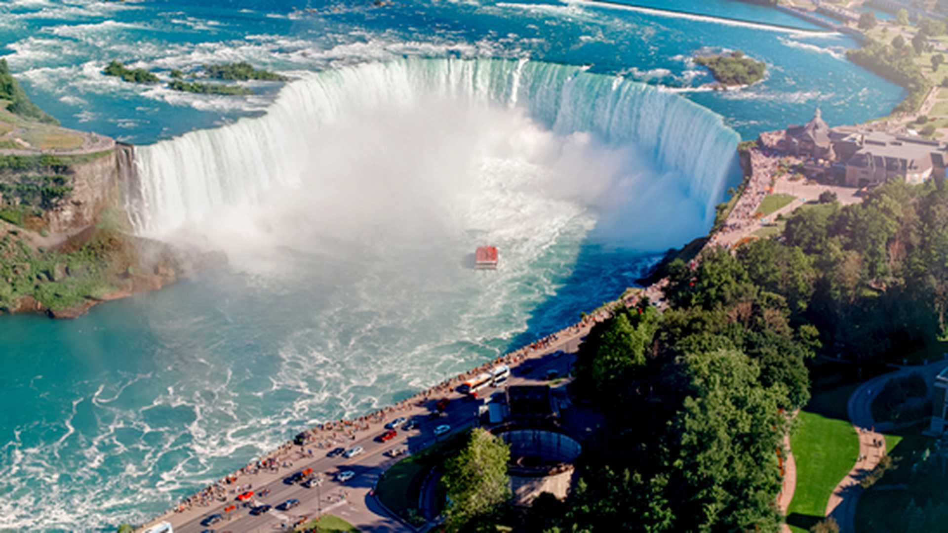 Aerial top landscape view of Niagara Falls  between United States of America and Canada. Horseshoe of Canadian waterfall on sunny day with the water tour boat.