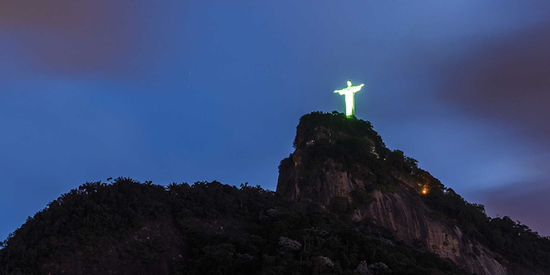 Christ the Redeemer on top of Corcovado Mountain with green lights at early night, Rio de Janeiro, Brazil