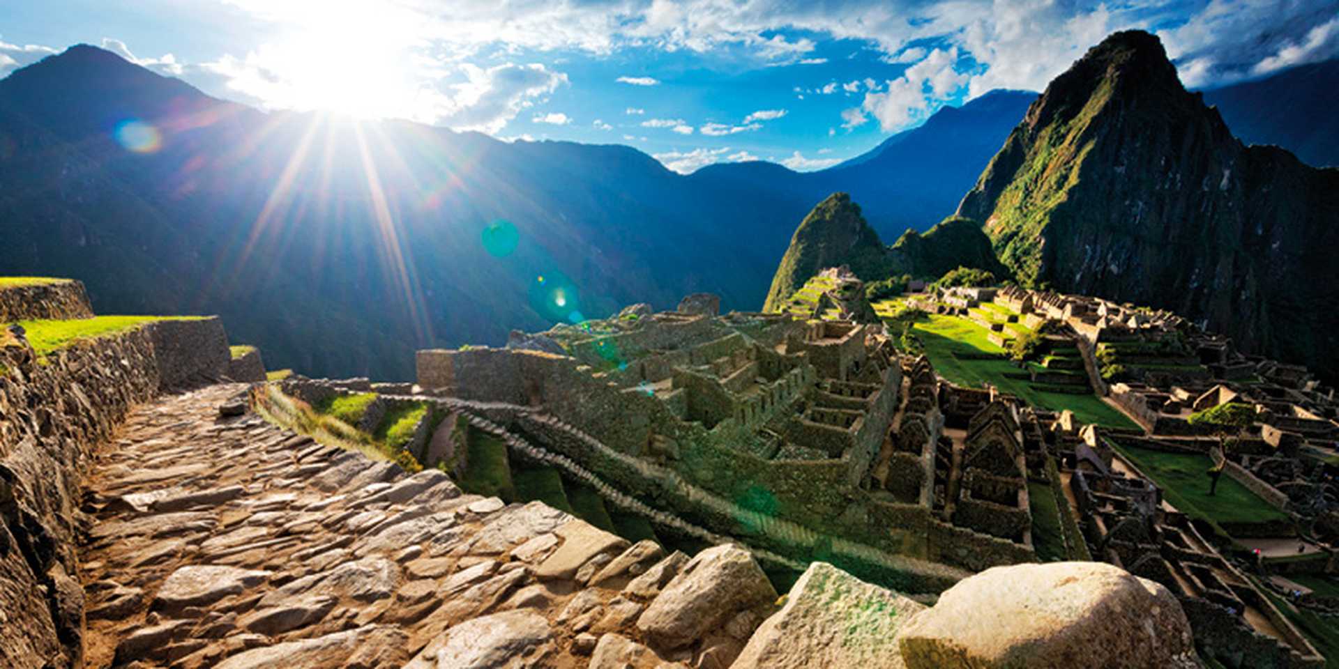 Evening sunburst over deserted paved pathway overlooking Machu Picchu ruins, Peru