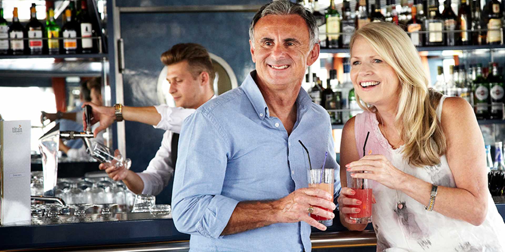 Couple holding drinks at the bar of a river cruise ship