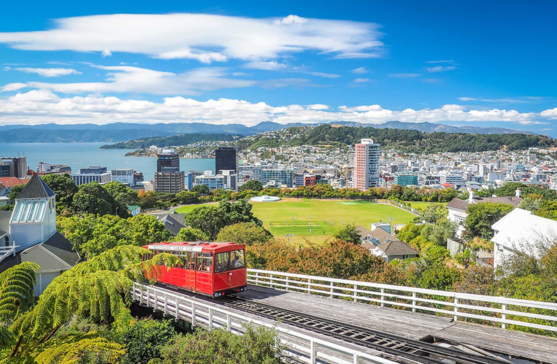 A tram travels up a hillside in Wellington, New Zealand, with a view across the city behind
