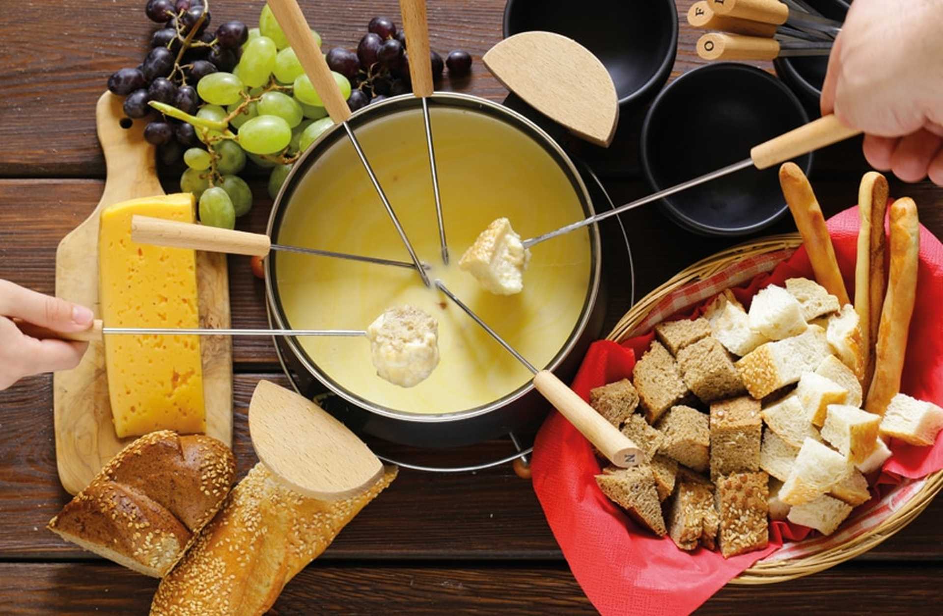 Diners dip bread into a pot of cheese fondue
