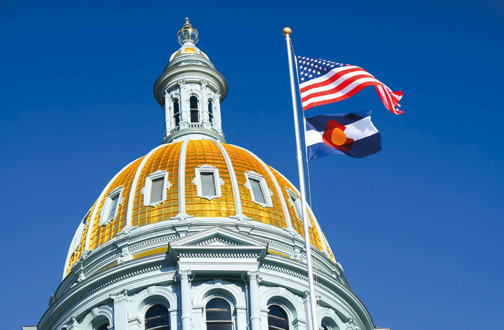 The American and Colorado flags flying at the Colorado state capitol building in Denver, USA