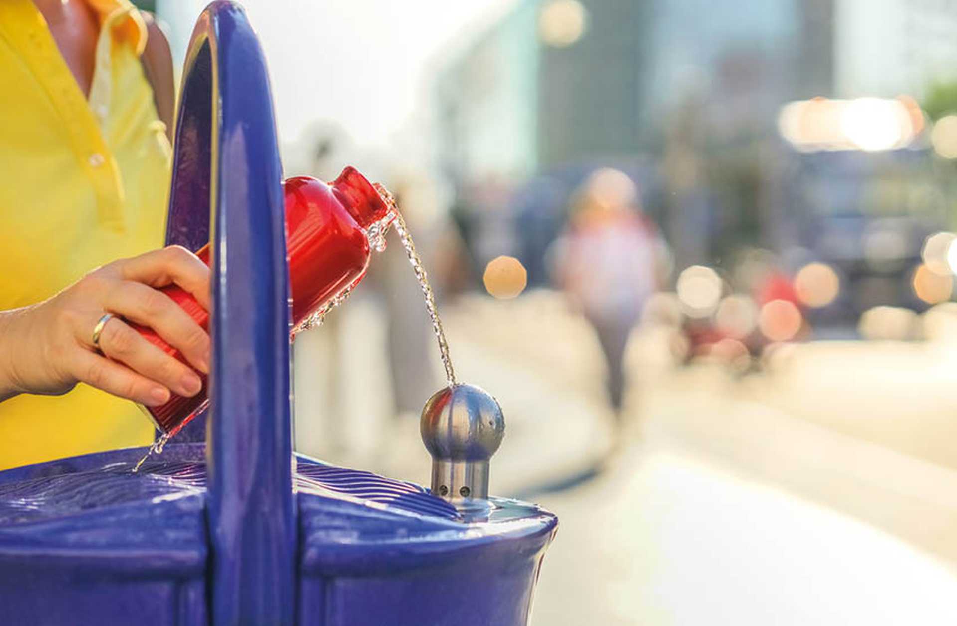 A woman fills a reusable bottle at a water fountain
