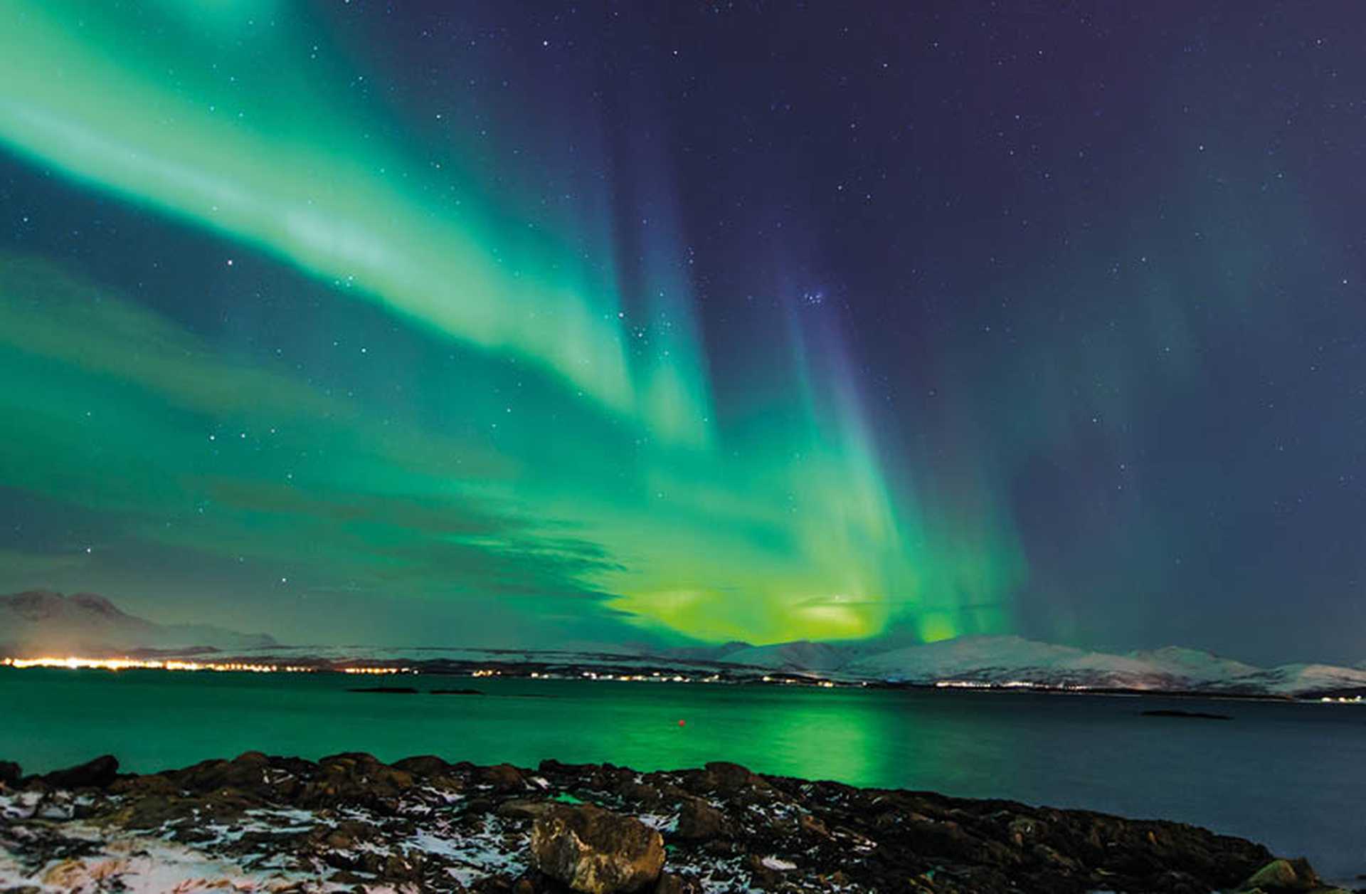 Northern Lights sweep across the sky above Tromso, Norway