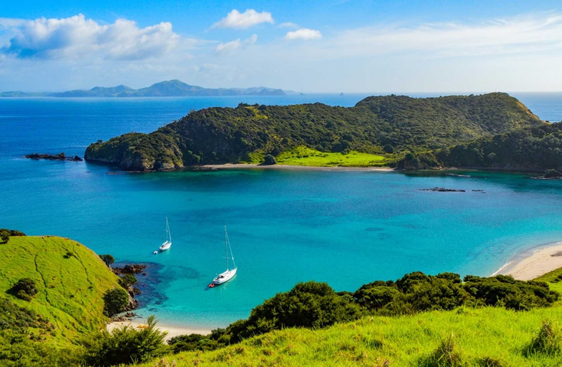 Yachts moor in a turquoise bay in Paihia, Bay of Islands. Visit North Island on TItan's New Zealand tours