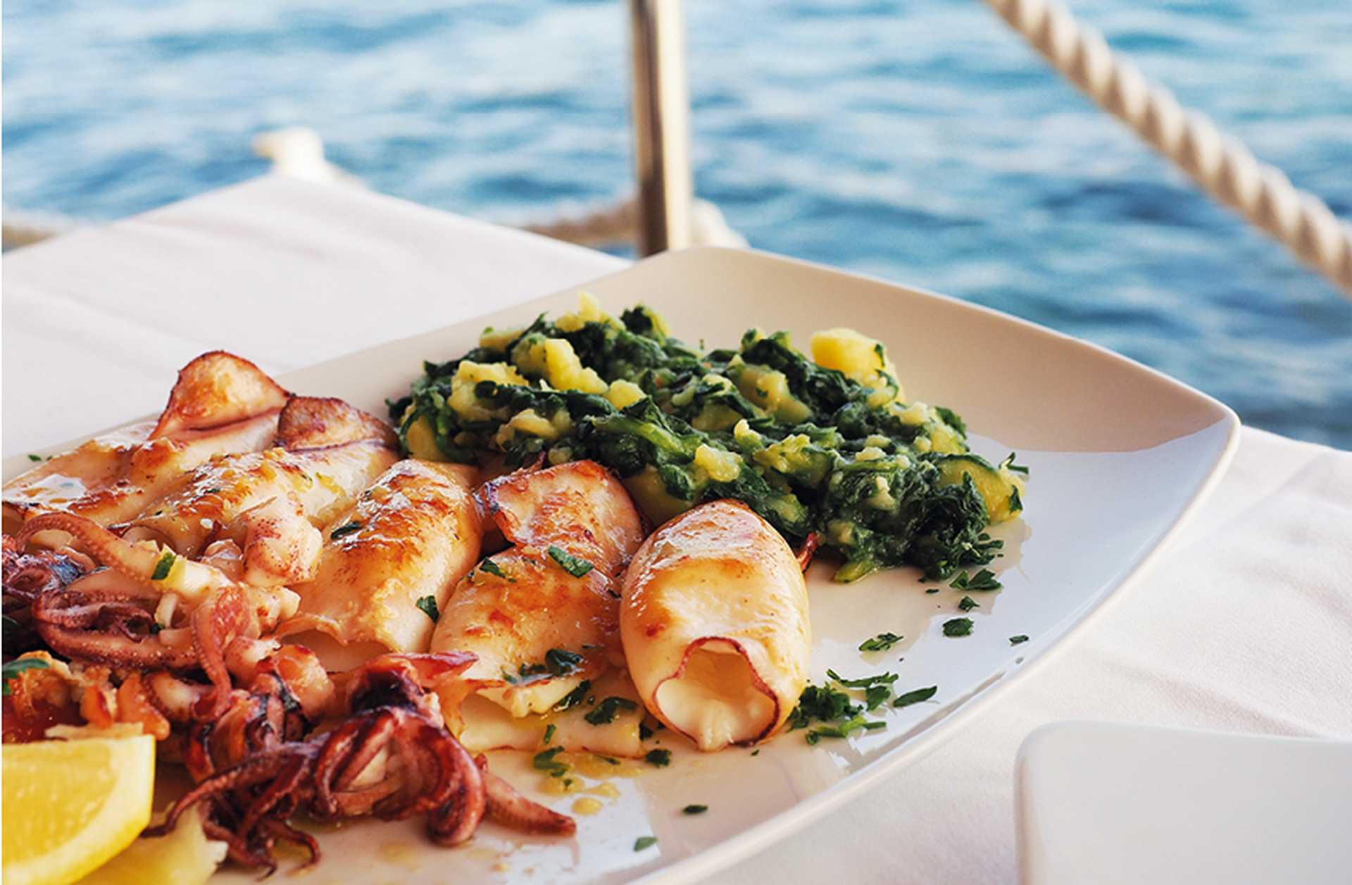 Grilled squid served on a white plate beside the sea in Croatia