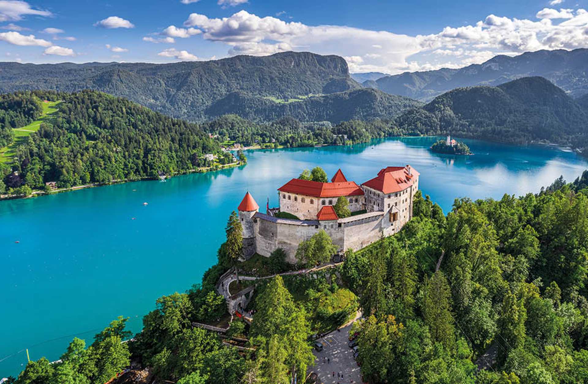 Aerial view of Bled Castle on a forested hill overlooking Lake Bled, Slovenia