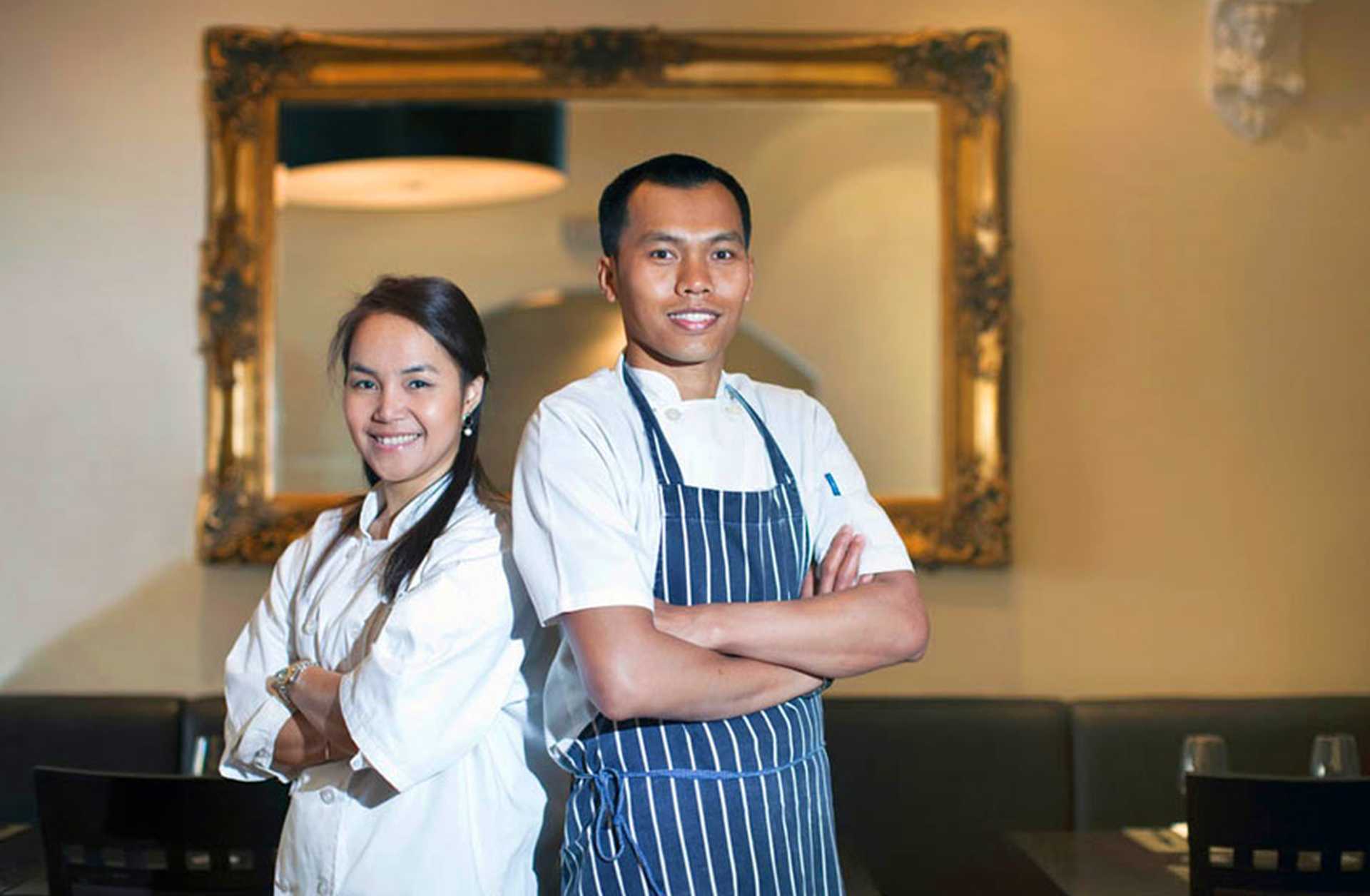Two chefs stand in their restaurant