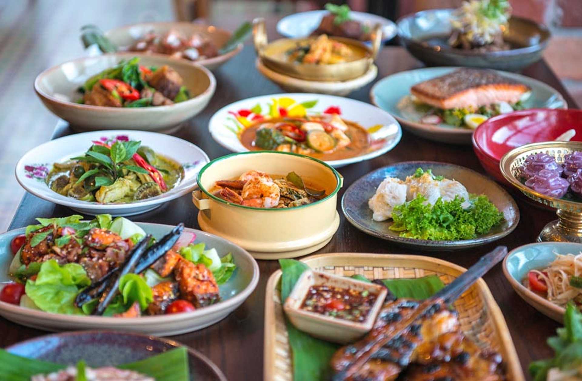 A table is filled with traditional Thai dishes