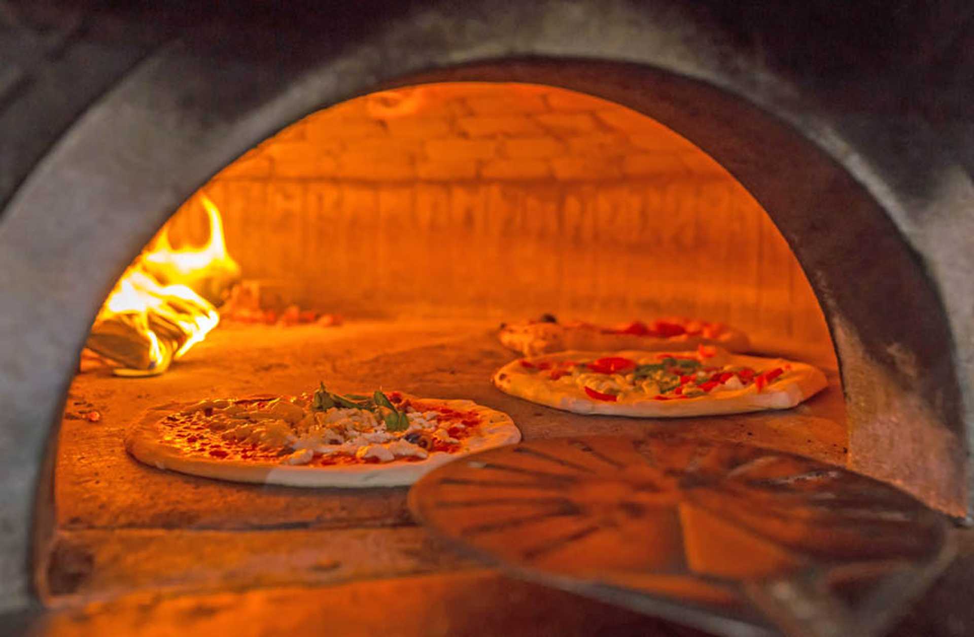 Italian pizzas cooking in a traditional wood-fired pizza oven