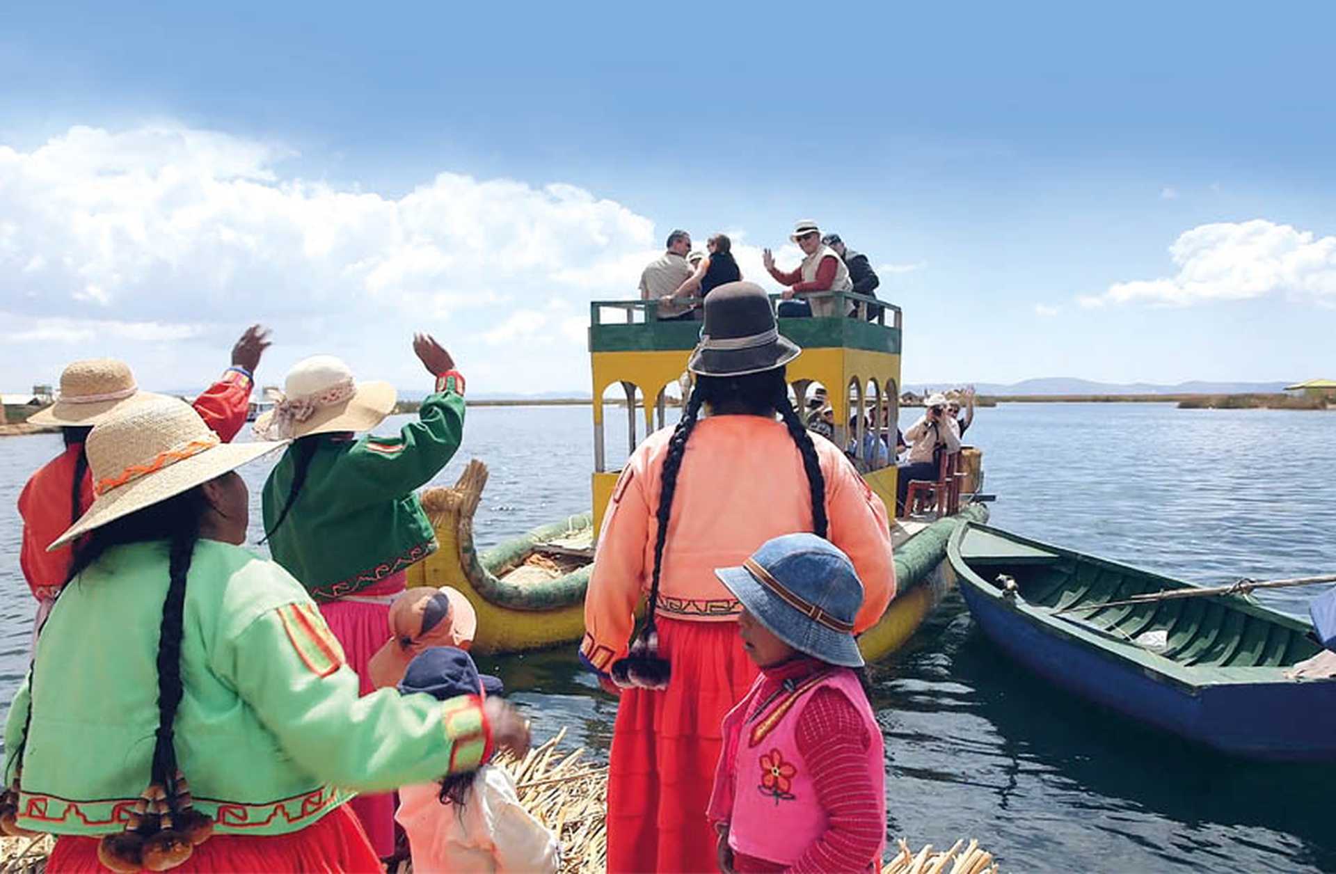 Locals wave to a boat of tourists on an island in Lake Titicaca, Peru