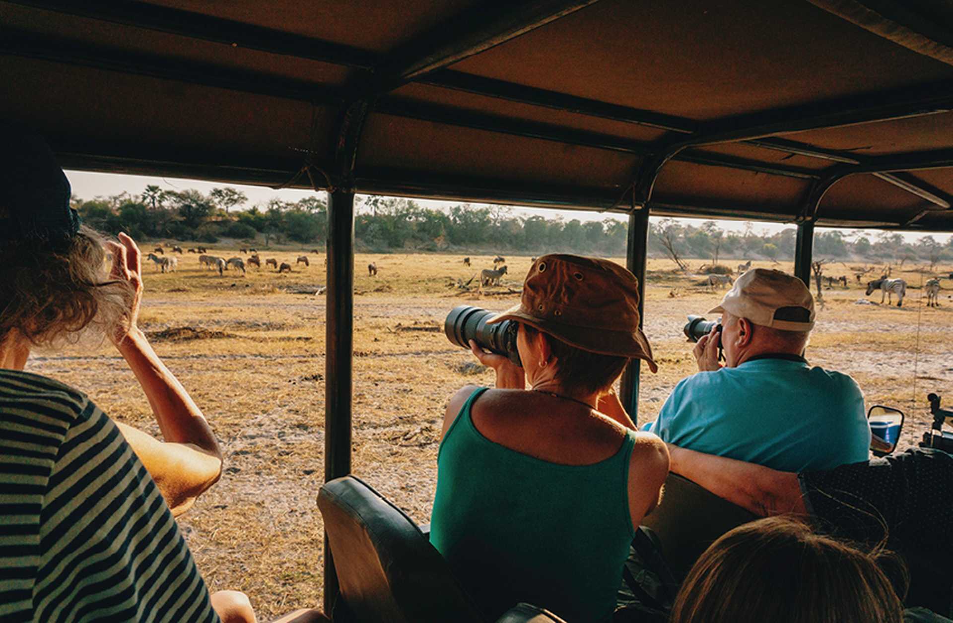 Tourists take photos of wildlife during a safari game drive