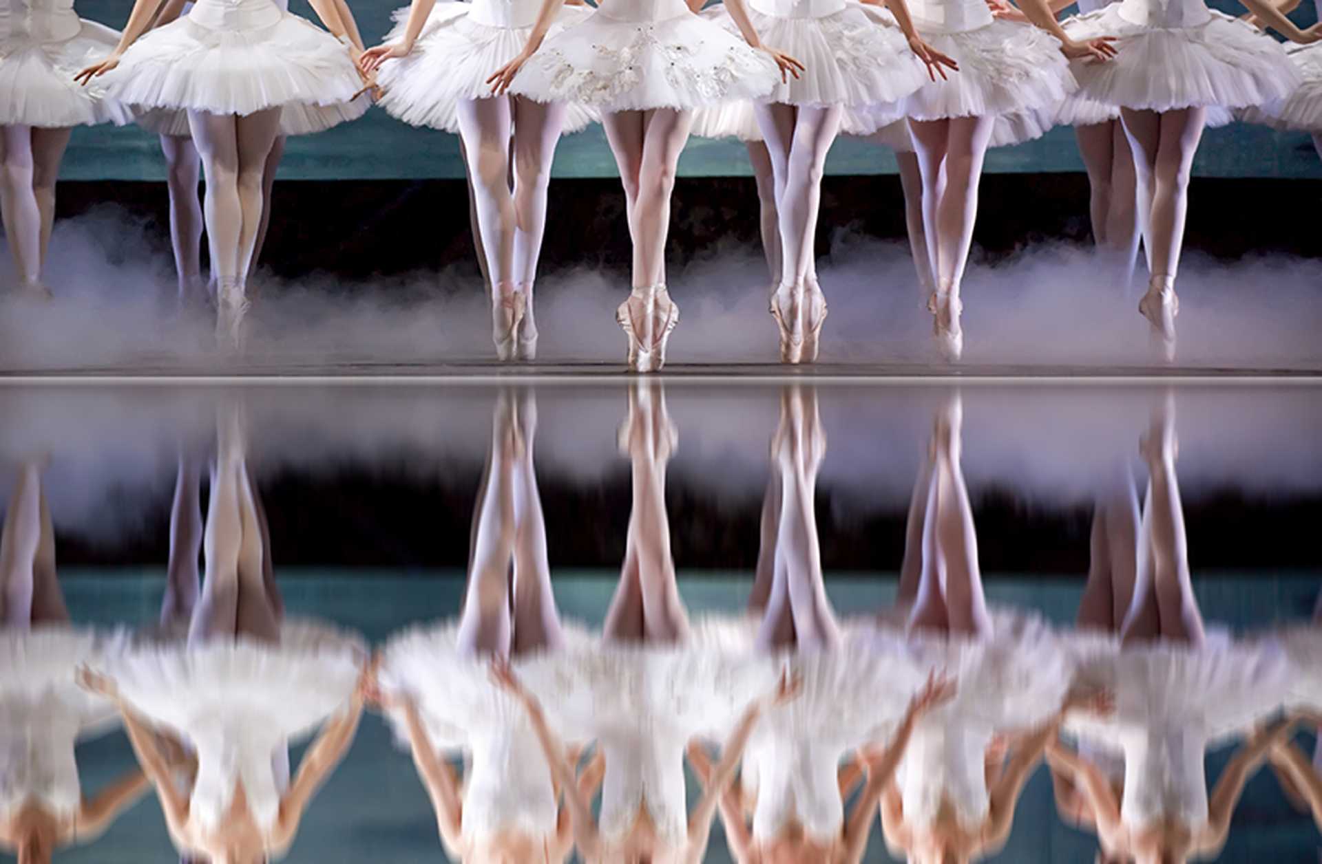 Ballet dancers in white tutus dance en pointe