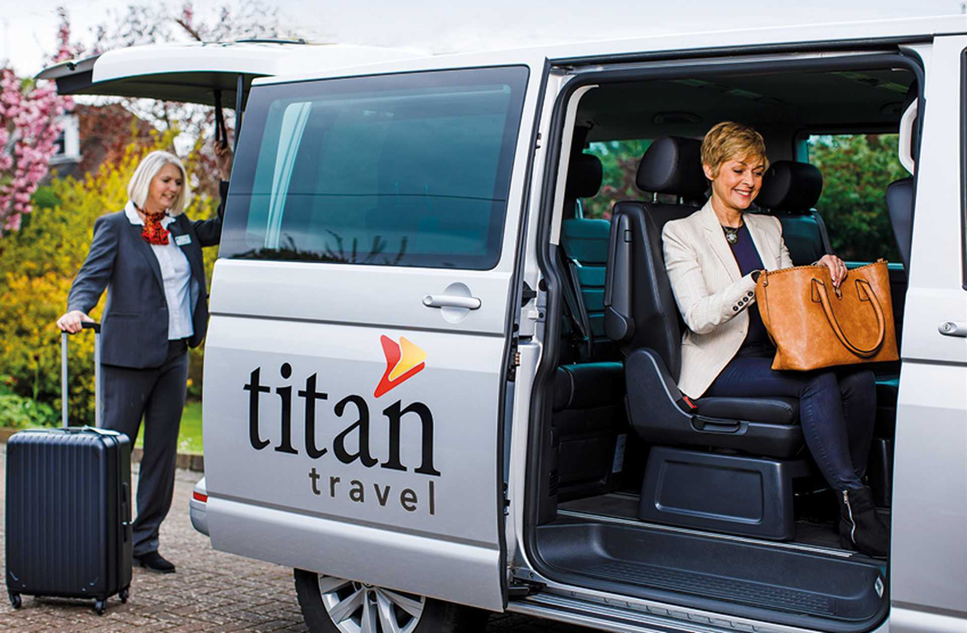 A solo traveller sits in a Titan VIP vehicle as the driver takes her suitcase