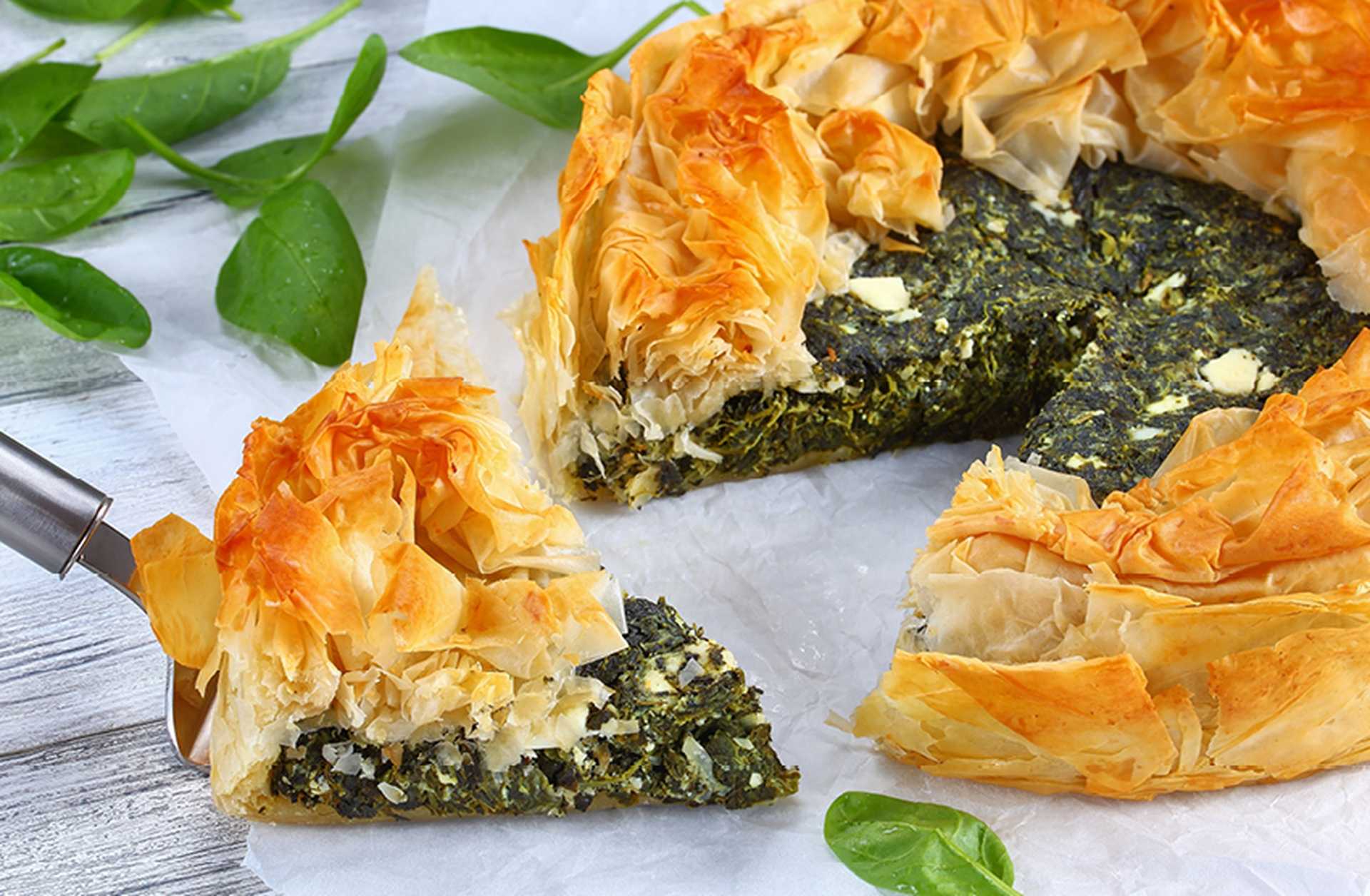 A slice of spanikopita, a traditional Greek spinach and feta pie, is cut
