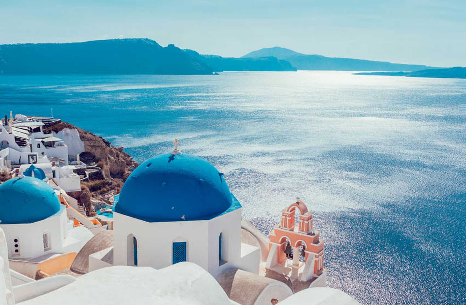 Church domes and bell tower overlook the waters of the caldera in Santorini, Greece