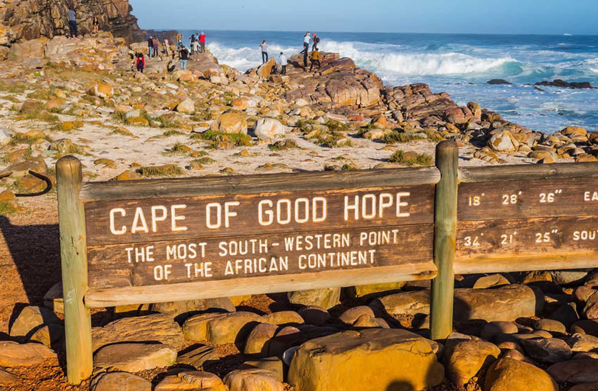 Wooden sign for the Cape of Good Hope sits on a rocky beach in South Africa