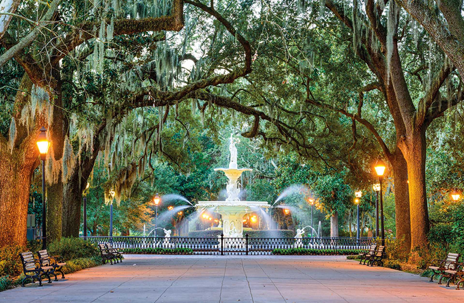 Trees draped in Spanish moss lead to Forsyth Park Fountain in Savannah, USA