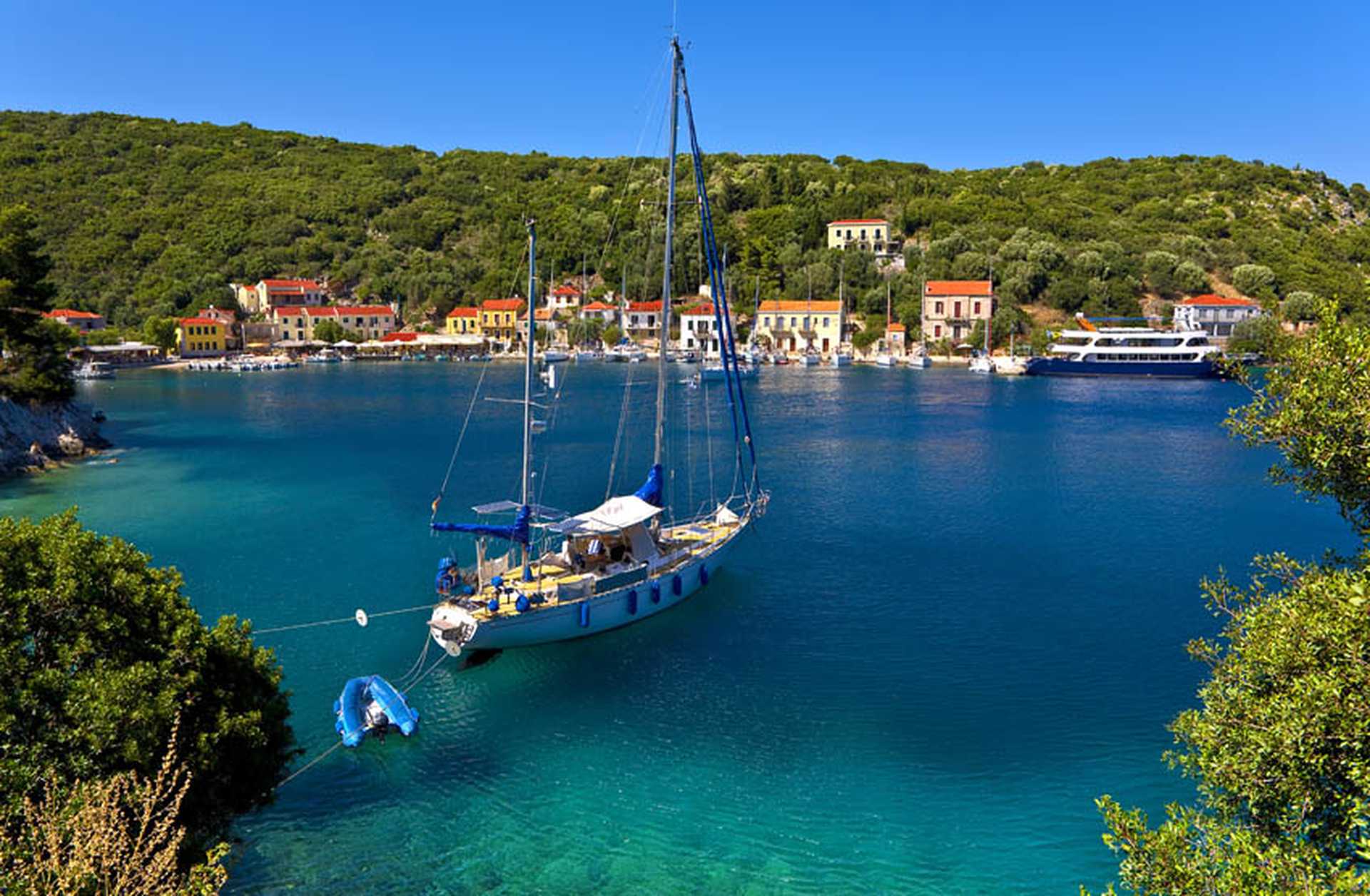 A boat bobs in the water in front of the village of Frikes in Ithaca, Greece