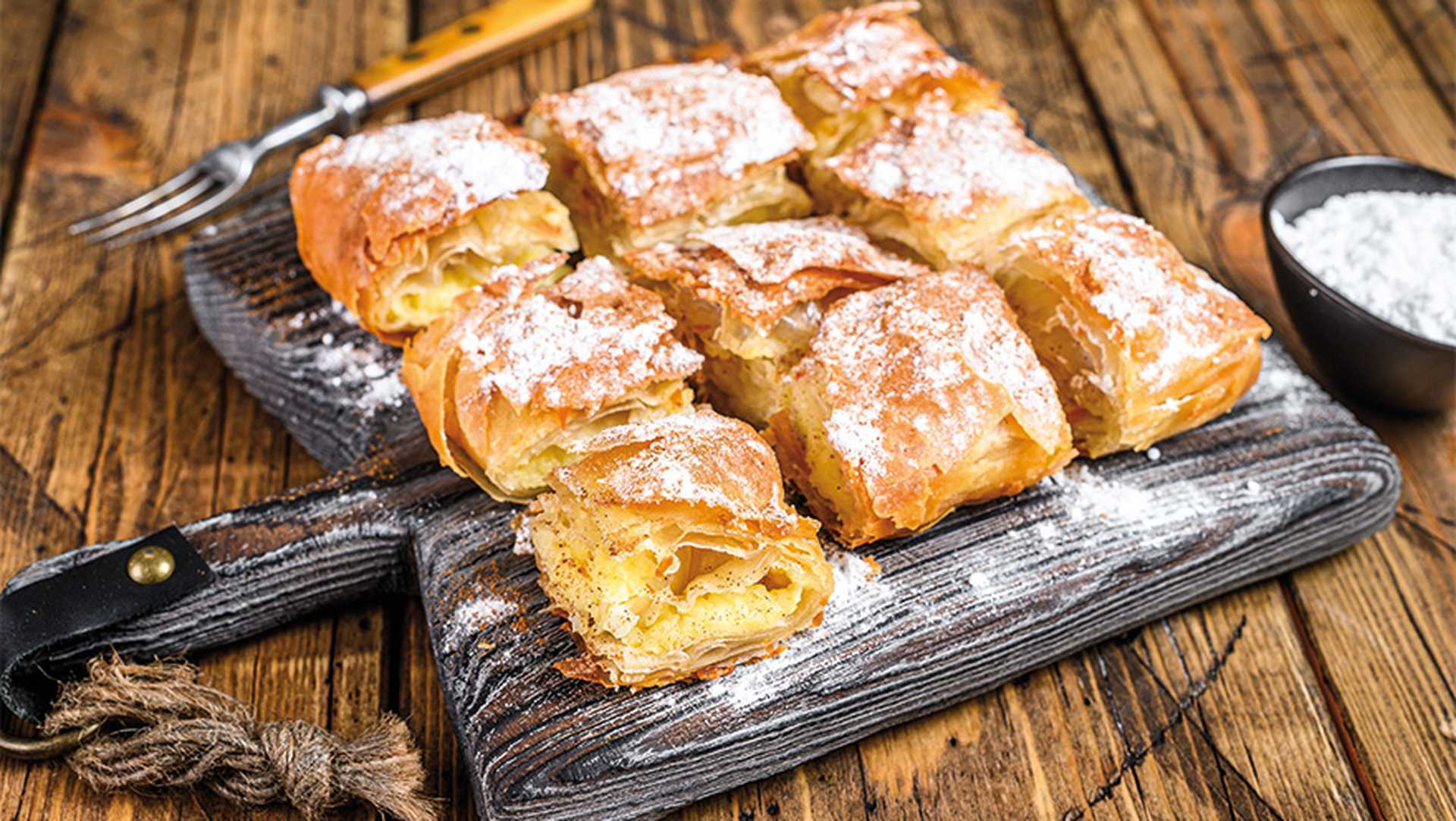 Greek pastry Bougatsa with phyllo dough and semolina custard cream. Wooden background. Top view.