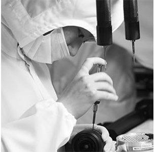 Mensch in Schutzanzug bearbeitet mit feinem Werkzeug das Objektiv