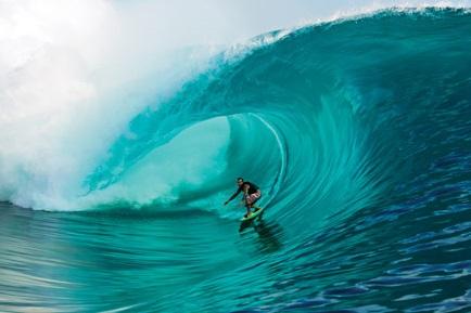 Surfer unter strahlend türkisfarbener Welle