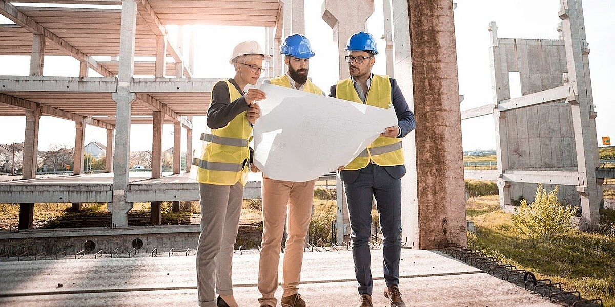 Three people in hard hats viewing design plans