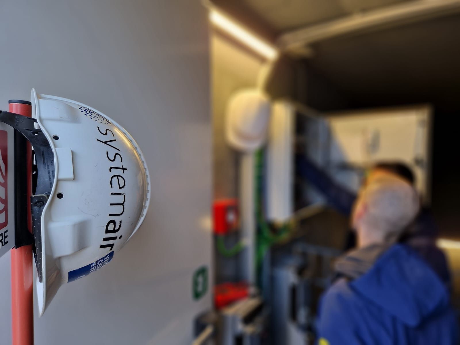 Photograph of a Systemair safety helmet with people in the background