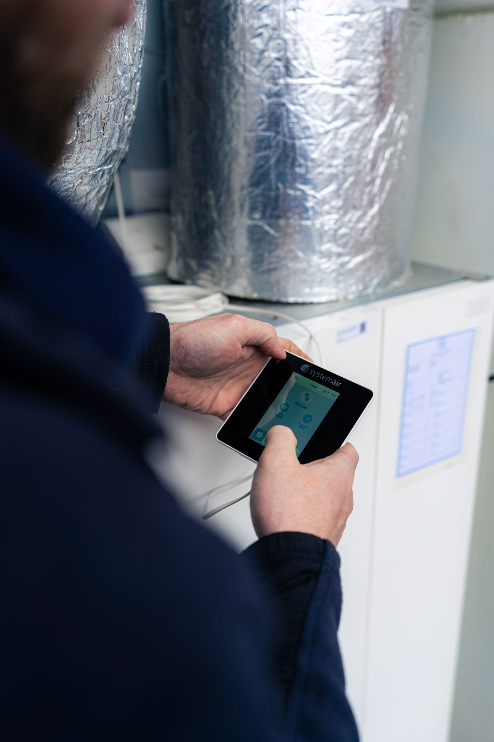 Photograph of a man holding a Systemair control device