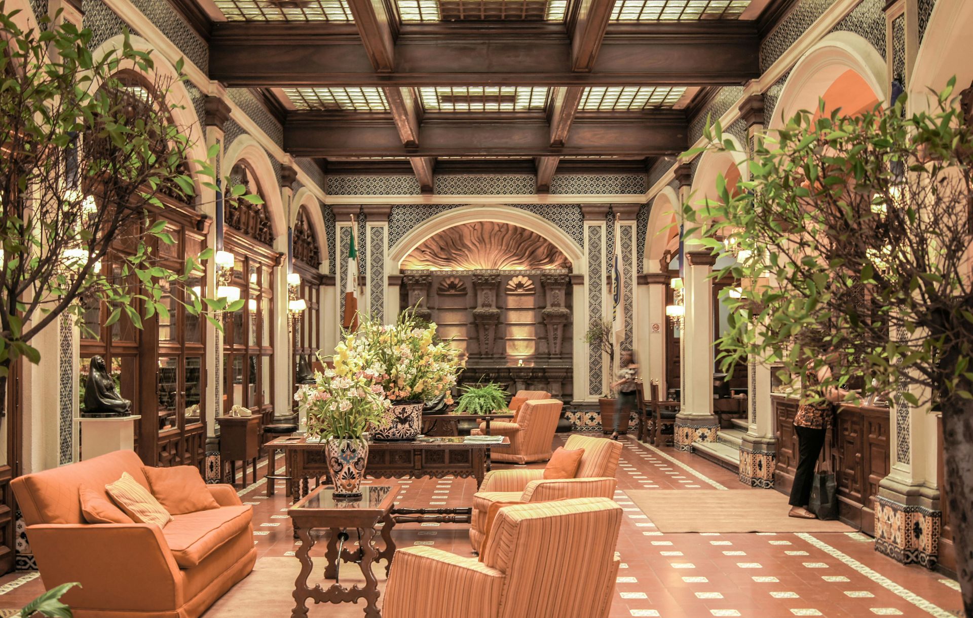 Hotel lobby with Orange Fabric Sofa With Three Throw Pillows Near Black Potted Plant