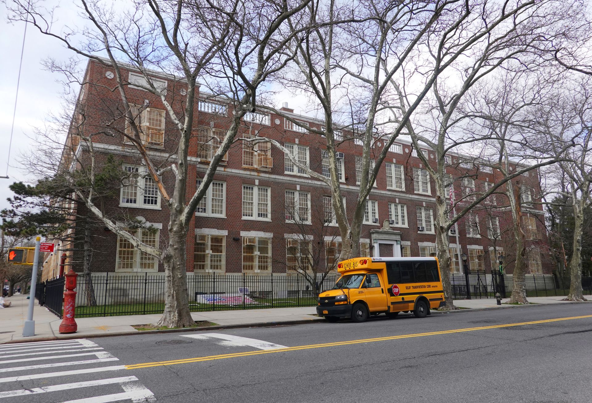 Outside of older school in New York with a small school bus in front of it