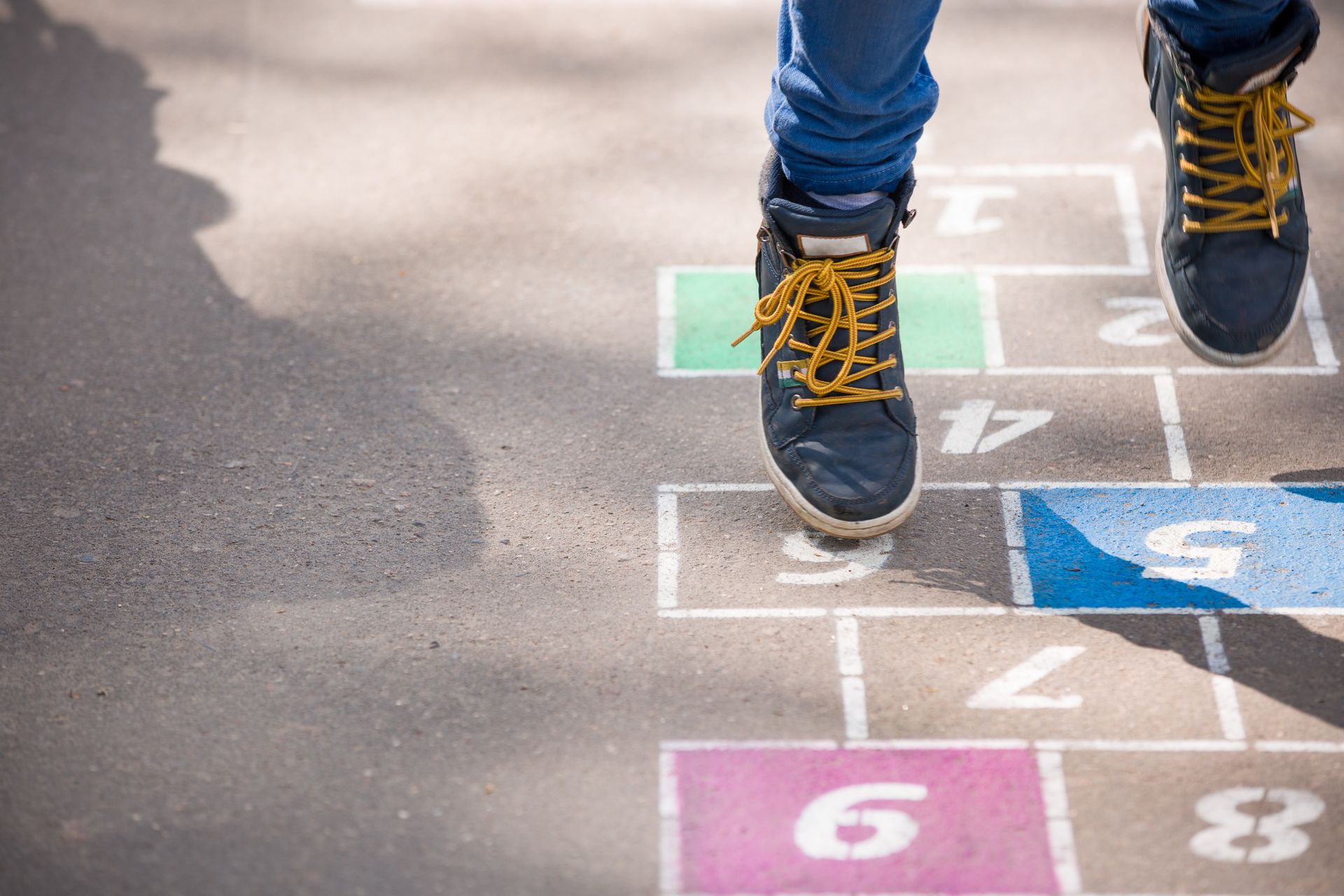 Stock photograph of a child playing at school and jumping on drawings on the ground