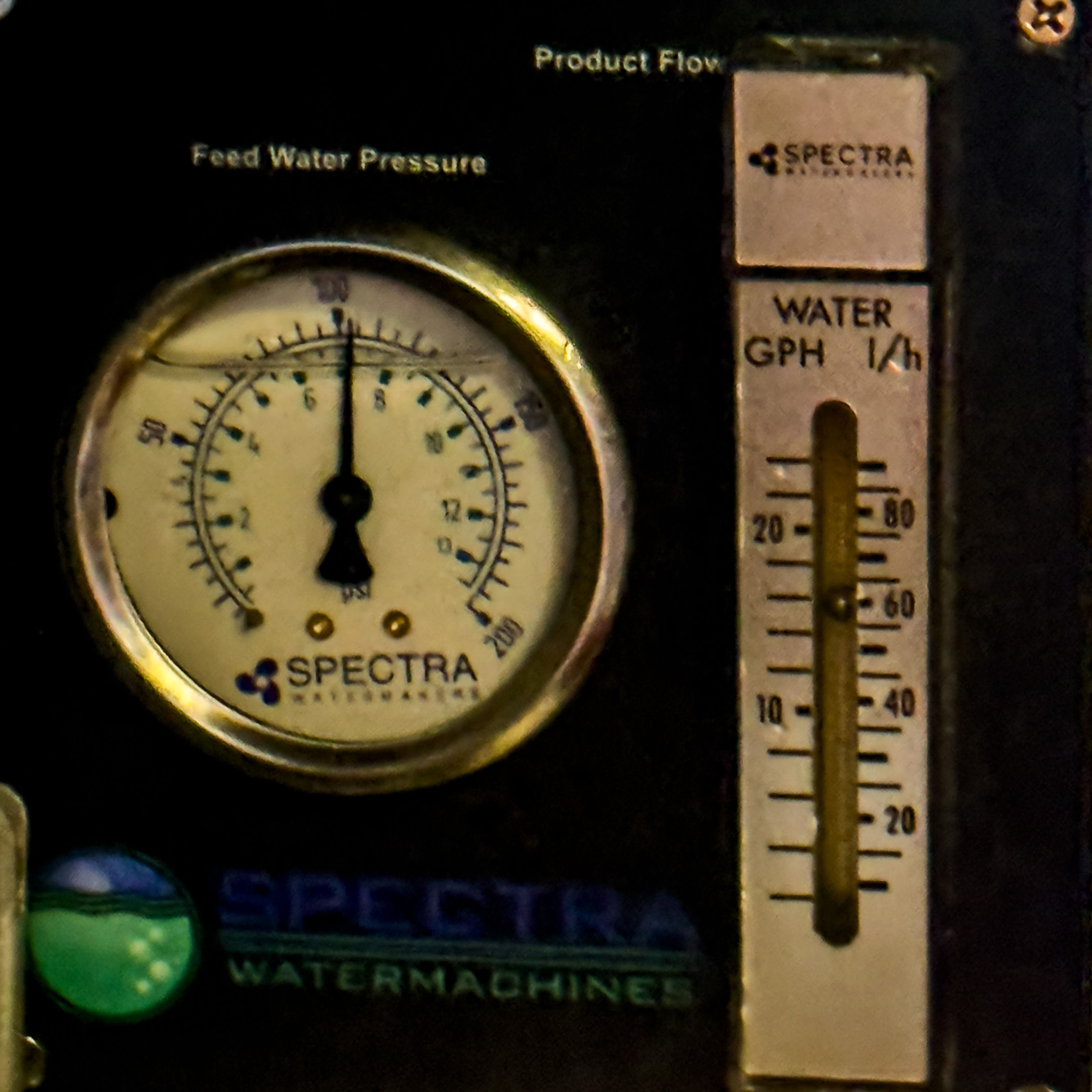 Close-up of a Spectra Watermachines gauge panel showing feed water pressure and water flow rate in gallons per hour.
