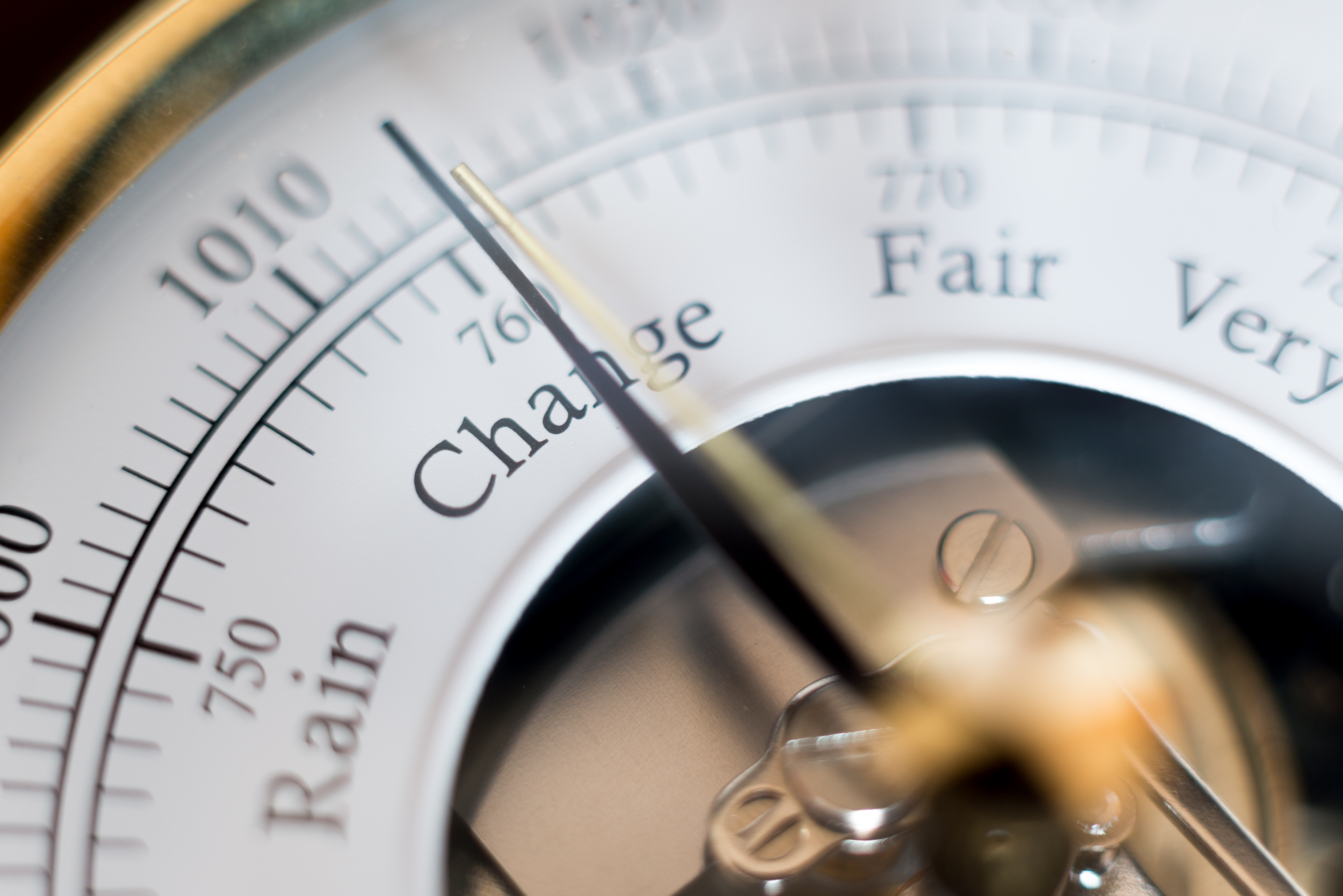 Close-up of a barometer dial showing the needle pointing to "Change" between "Rain" and "Fair".