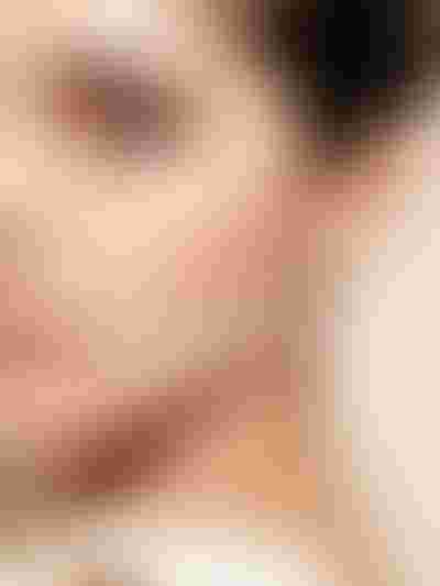 Close-up of a woman wearing a gold pearl earring with rhinestone accents.