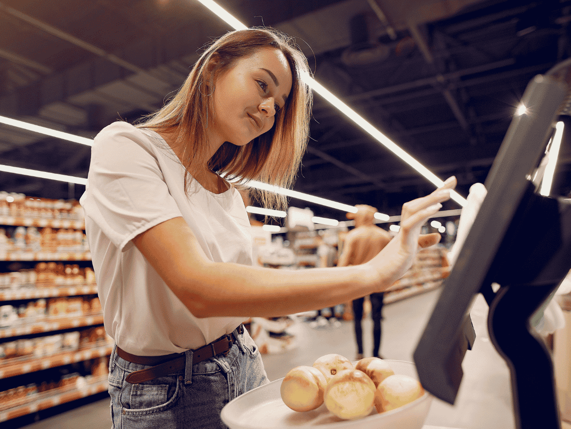 Customer using a self-service touchscreen display in a supermarket.
