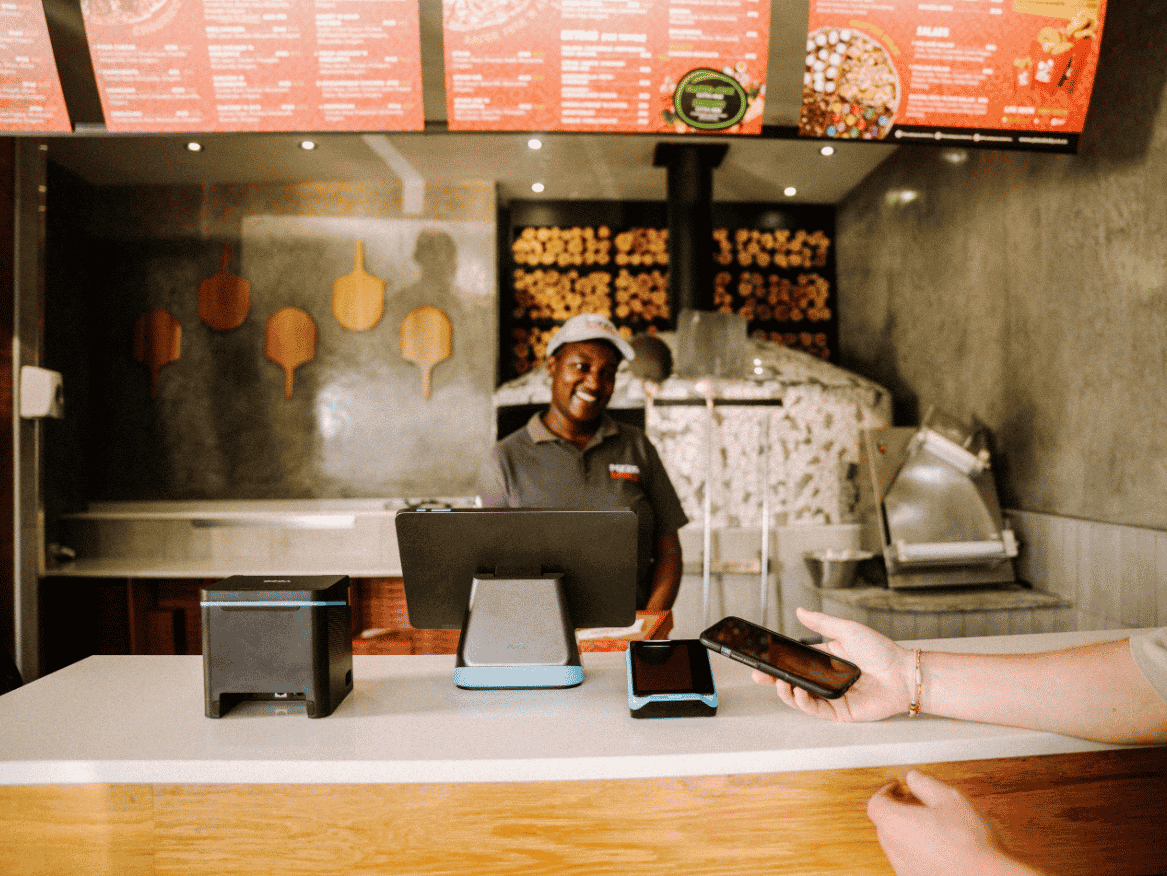 Restaurant employee using a countertop point of sale system while serving a customer.