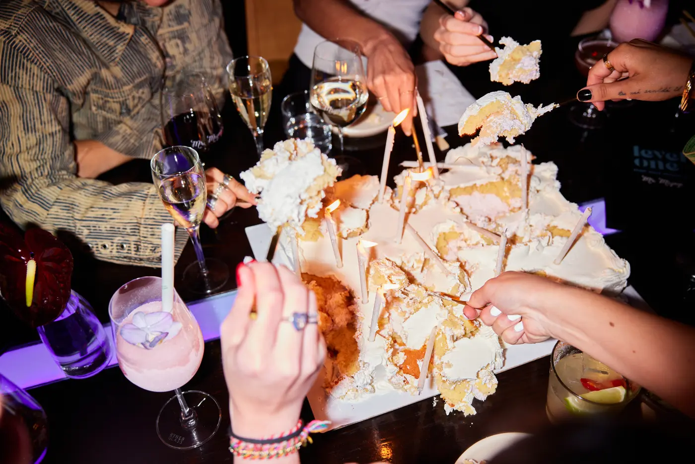 Friends sharing a large celebration cake with chopsticks