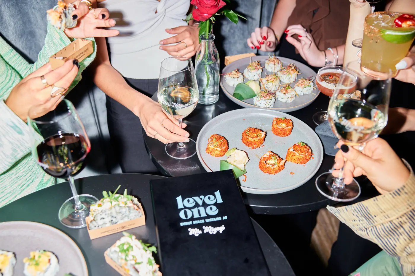 Guests reaching for shared plates and cocktails around a black table