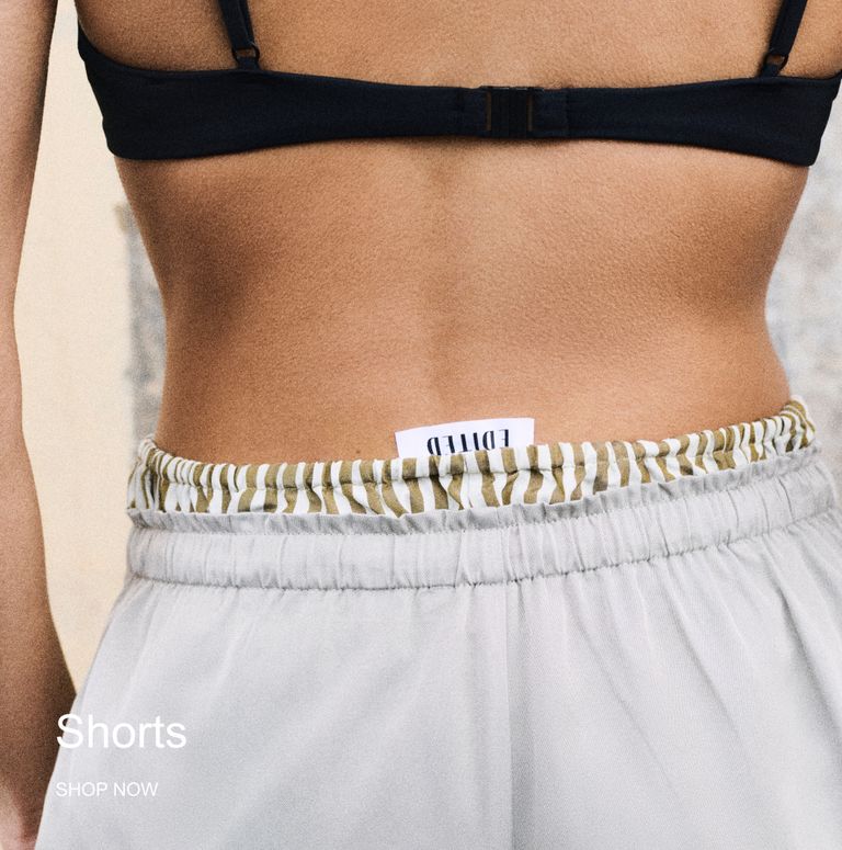 A person in a black bikini top and striped shorts with an "EDITED" label. Text at the bottom reads "Shorts, SHOP NOW."